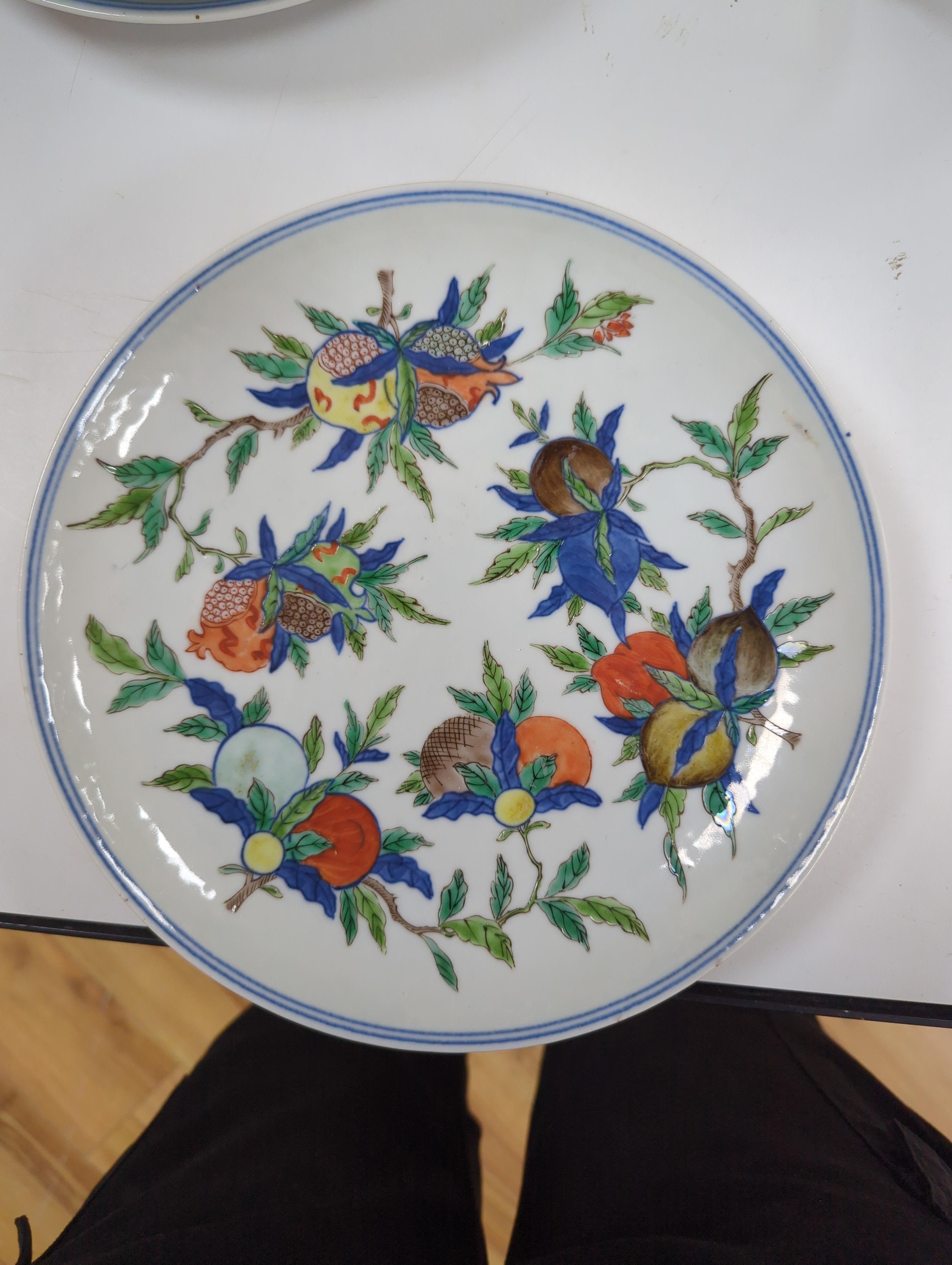 An 18th century Chinese famille rose bowl and a group of five Chinese wucai plates, each decorated with fruit, the bowl 23cm in diameter